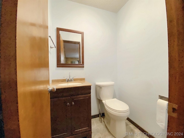 bathroom with tile patterned floors, vanity, toilet, and a textured ceiling