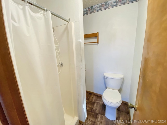 bathroom featuring a shower with curtain, toilet, and parquet floors