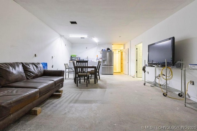 living area featuring unfinished concrete floors and visible vents