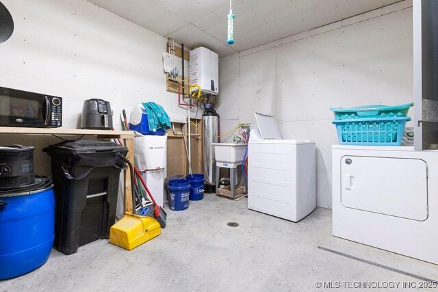 laundry area with laundry area, washing machine and dryer, and water heater