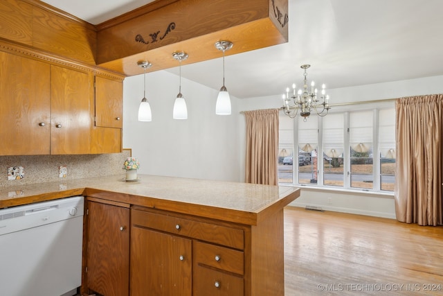 kitchen with pendant lighting, dishwasher, backsplash, an inviting chandelier, and kitchen peninsula