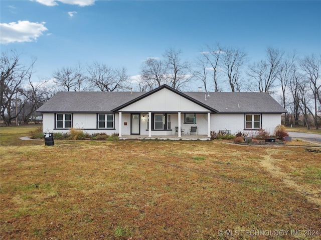 ranch-style home featuring covered porch and a front yard