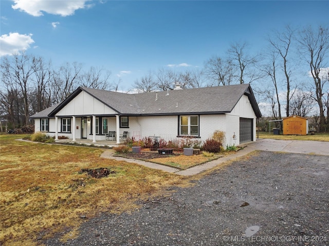 view of front of house featuring a storage unit, covered porch, a front lawn, and a garage