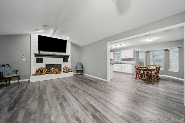 living room featuring hardwood / wood-style flooring, a fireplace, and lofted ceiling with beams