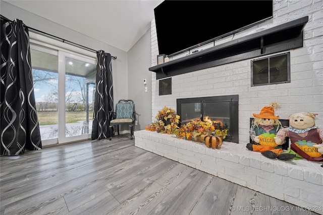 living room featuring wood-type flooring, lofted ceiling, and a fireplace