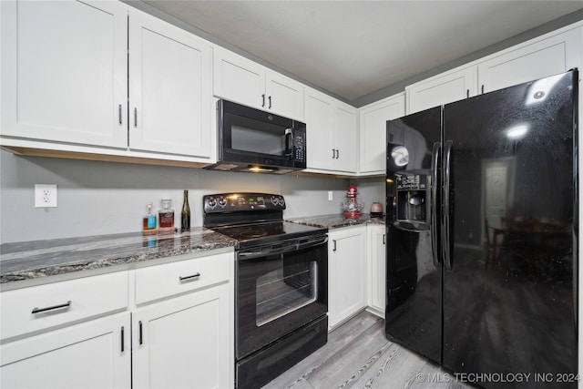 kitchen with white cabinets, dark stone counters, light hardwood / wood-style floors, and black appliances