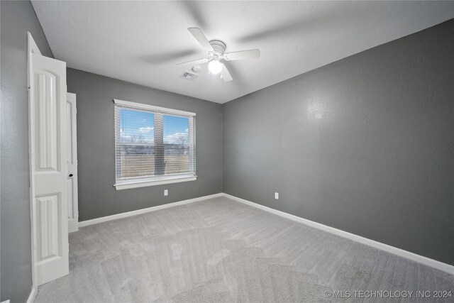 carpeted spare room with ceiling fan