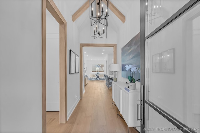 hall featuring a towering ceiling and light wood-type flooring