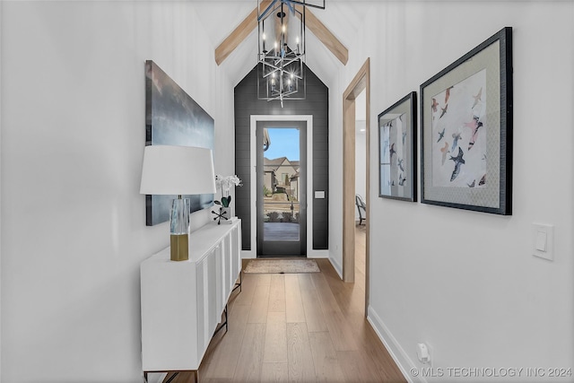 doorway featuring lofted ceiling, hardwood / wood-style floors, and a notable chandelier