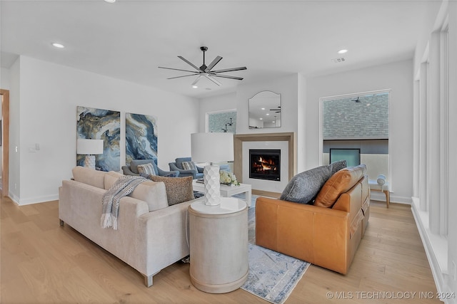 living room with ceiling fan, plenty of natural light, and light wood-type flooring