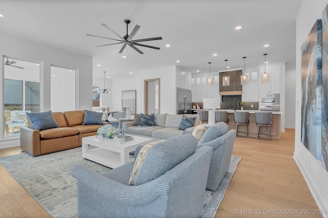 living room featuring sink, ceiling fan, and light hardwood / wood-style floors