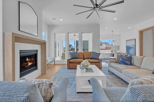 living room featuring ceiling fan, a fireplace, and light hardwood / wood-style floors