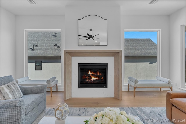 living room with hardwood / wood-style floors, a high end fireplace, and ceiling fan