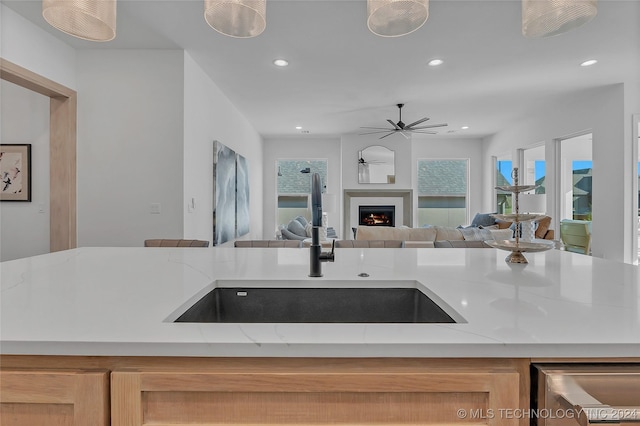 kitchen featuring light stone countertops, sink, light brown cabinets, and plenty of natural light