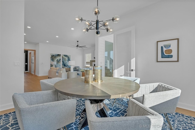 dining room with ceiling fan with notable chandelier and hardwood / wood-style floors