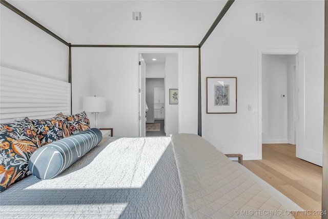 bedroom featuring connected bathroom, hardwood / wood-style floors, and a towering ceiling