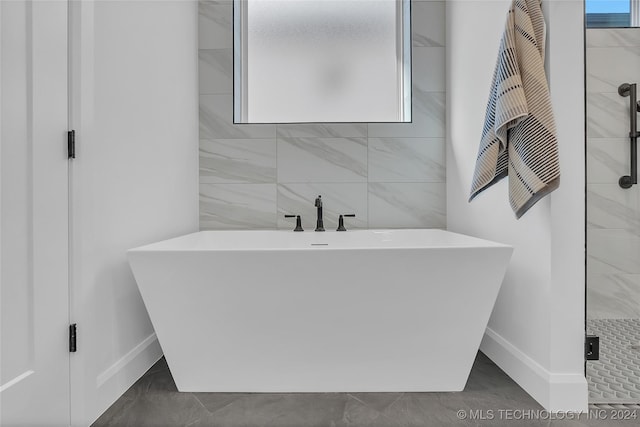 bathroom featuring shower with separate bathtub and tile walls