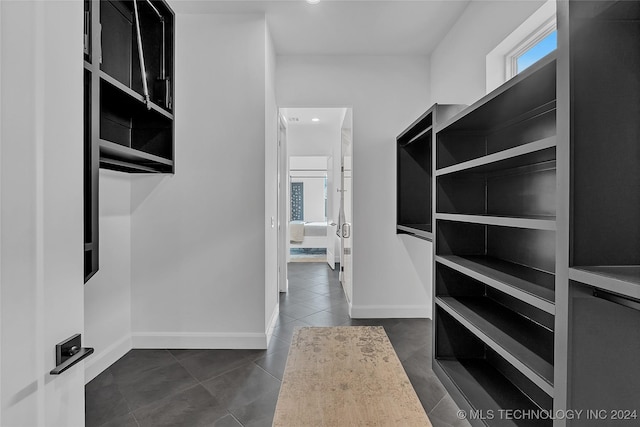 spacious closet featuring dark tile patterned flooring