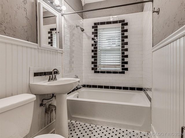 bathroom featuring toilet, tile patterned floors, and tiled shower / bath