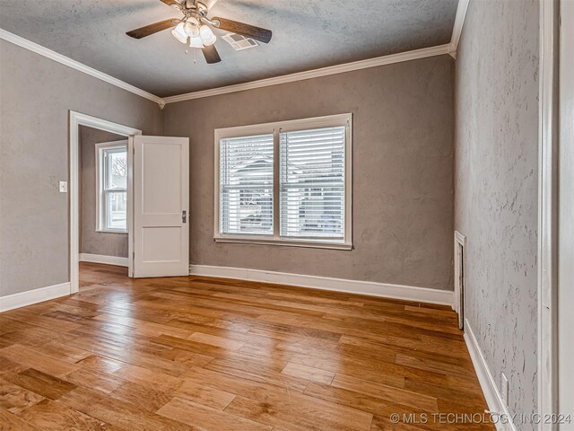 spare room featuring crown molding, ceiling fan, a textured ceiling, and light wood-type flooring