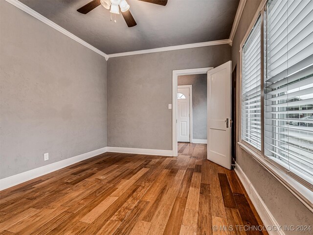 empty room with hardwood / wood-style flooring, ceiling fan, ornamental molding, and a wealth of natural light