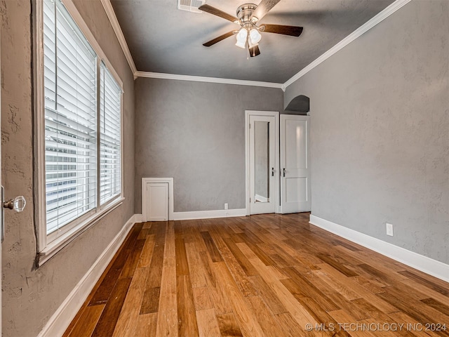 empty room with wood-type flooring, ceiling fan, and crown molding