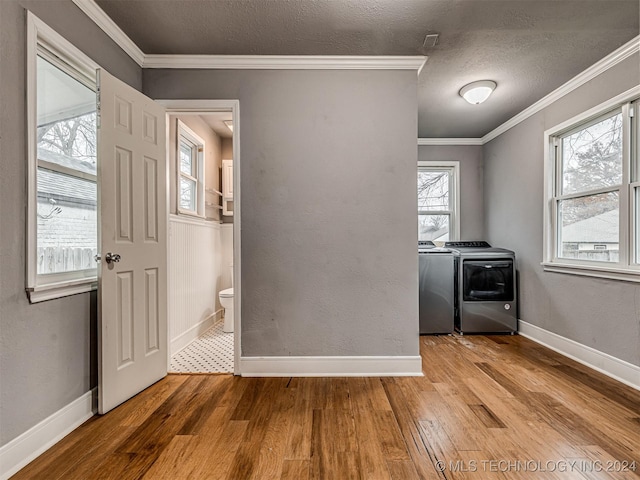 interior space with independent washer and dryer, a textured ceiling, light hardwood / wood-style flooring, and crown molding