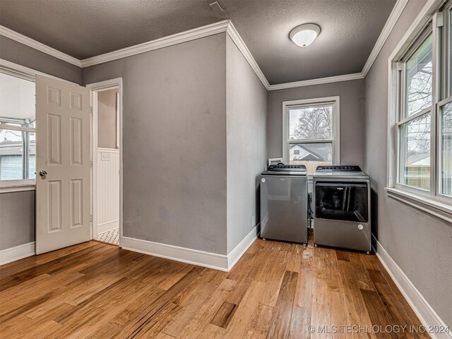 laundry area featuring separate washer and dryer, plenty of natural light, light hardwood / wood-style floors, and a textured ceiling