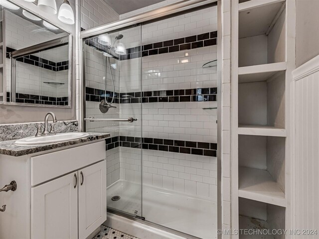 bathroom featuring built in features, vanity, and a shower with shower door