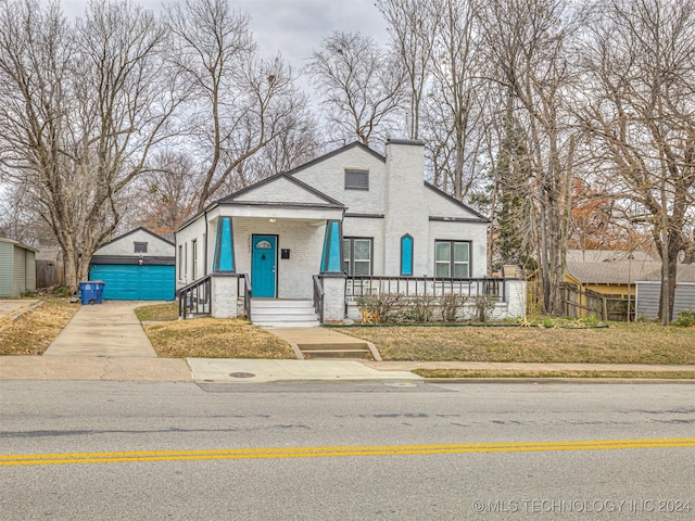 view of front of house featuring a porch, an outbuilding, a front yard, and a garage