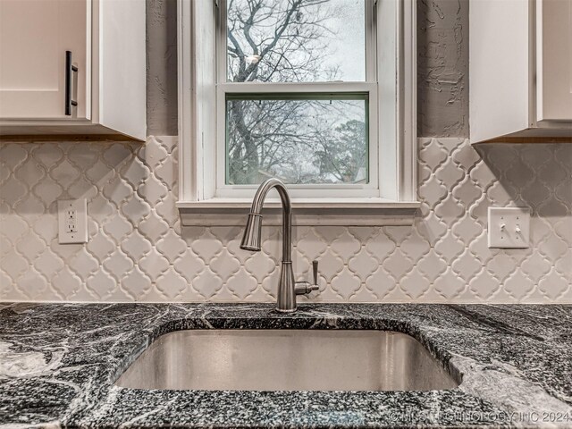 kitchen featuring white cabinets, sink, dark stone counters, and tasteful backsplash