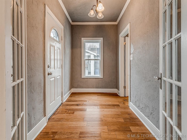 foyer entrance with french doors, crown molding, a notable chandelier, and light hardwood / wood-style flooring