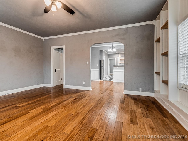 unfurnished living room featuring ceiling fan with notable chandelier, crown molding, and light hardwood / wood-style flooring