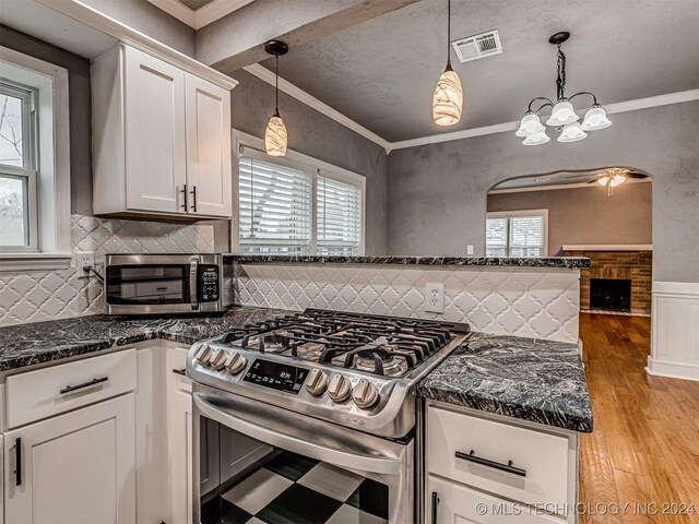 kitchen featuring white cabinets, crown molding, hanging light fixtures, and stainless steel range with gas stovetop