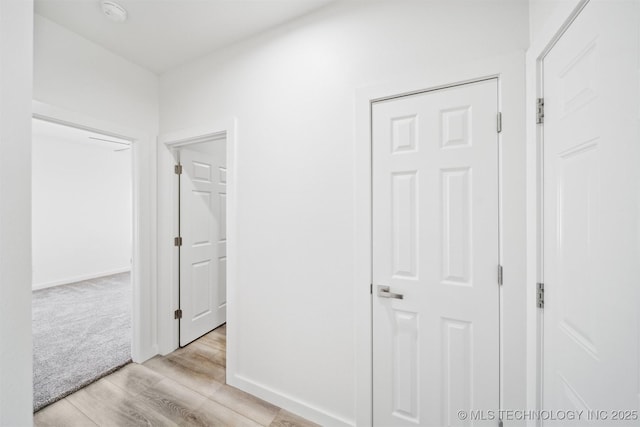 hall with baseboards and light wood-style floors