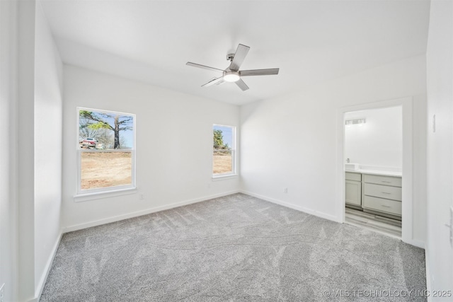 unfurnished bedroom with baseboards, light carpet, ensuite bath, and a ceiling fan