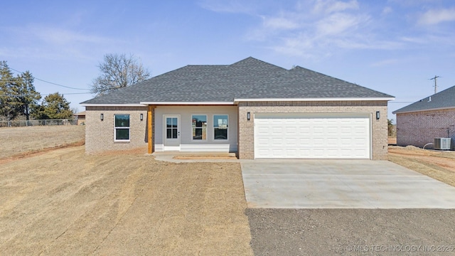 view of front of property with cooling unit, brick siding, concrete driveway, and a shingled roof