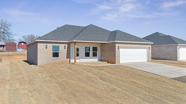 view of front of home with concrete driveway, a garage, brick siding, and roof with shingles