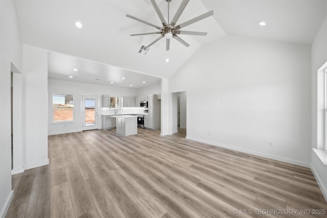 unfurnished living room featuring visible vents, baseboards, a ceiling fan, and light wood finished floors