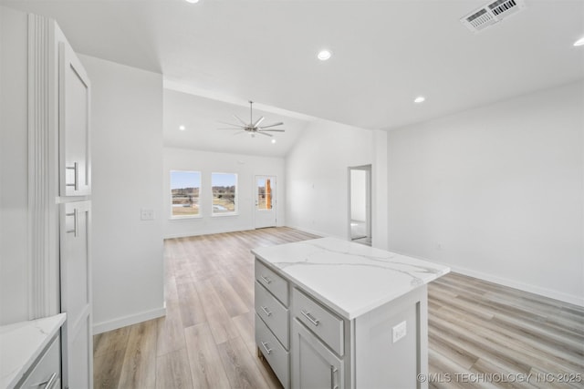 kitchen featuring visible vents, a kitchen island, light wood-style floors, and open floor plan