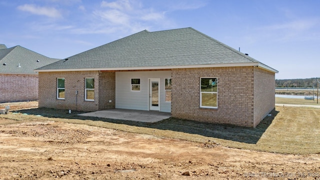 back of property featuring brick siding, roof with shingles, and a patio area