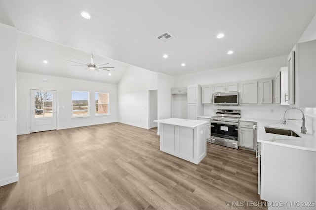 kitchen with visible vents, a center island, light wood-type flooring, stainless steel appliances, and a sink