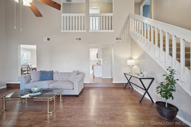 living room featuring ceiling fan, dark hardwood / wood-style flooring, and a towering ceiling