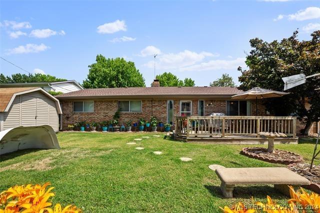 rear view of house with a lawn, a storage shed, and a wooden deck