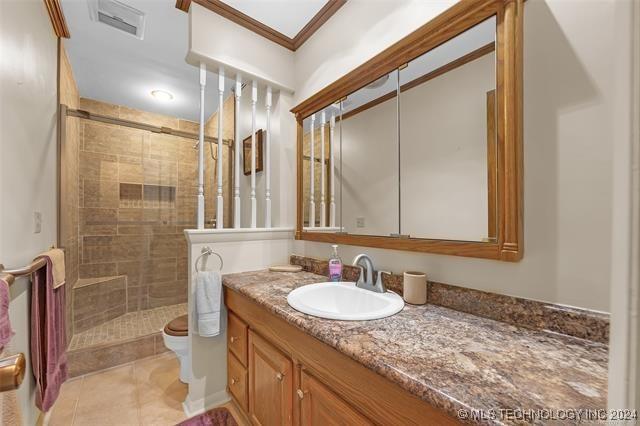 bathroom with toilet, vanity, a shower with door, and crown molding