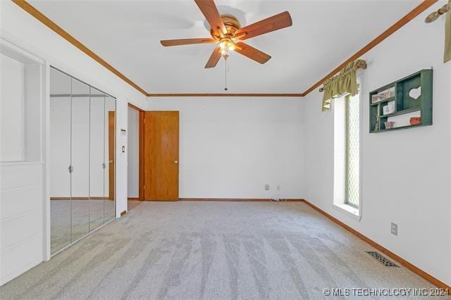 unfurnished bedroom featuring ceiling fan, ornamental molding, and light carpet