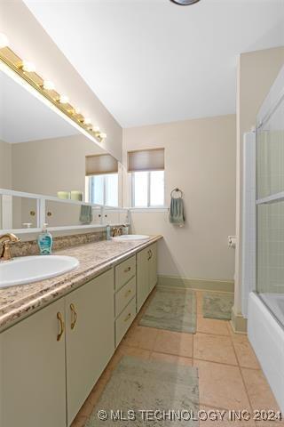 bathroom featuring enclosed tub / shower combo, tile patterned flooring, and vanity