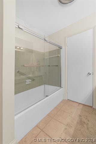 bathroom with bath / shower combo with glass door and tile patterned flooring