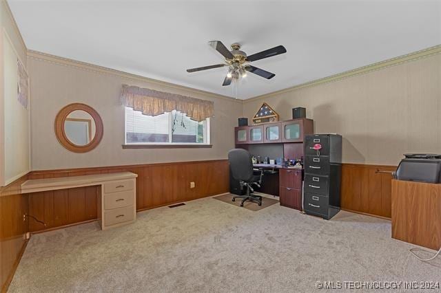 carpeted home office featuring ceiling fan, ornamental molding, and wooden walls