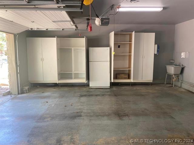 garage with sink, a garage door opener, and white fridge